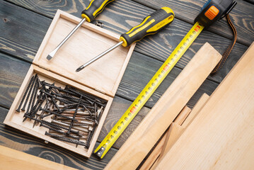 Meter, screws, screwdrivers and wooden bars on the carpenter workbench background.