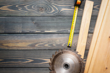 Meter, wooden planks and circular saw blade on the carpenter workbench flat lay background with...