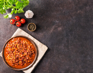 Stewed oxtails with vegetables in a wooden plate on a dark background with fresh tomatoes and herbs. Meat stew. The concept of traditional Spanish cuisine.