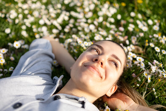 Beautiful young woman lying down in daisy field. She is so happy. 