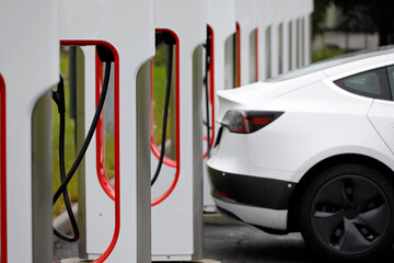 An electric car recharging its batteries at a charging station - 545760900