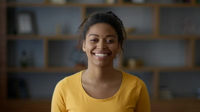Positive mood. Young happy african american woman laughing to camera, posing at home interior, slow motion