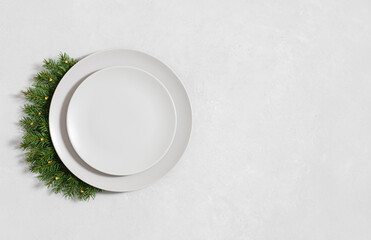 Christmas minimal table setting with empty plate and fir branches on gray background. View from above. Space for text.