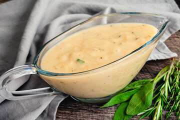 Classic Southern Gravy Made with Fresh Herbs in a Gravy Boat: Homemade gravy in a glass gravy boat with fresh herbs on the side