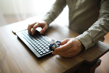A man with a gift in his hand sits in front of the monitor screen. Order a gift for home and office.