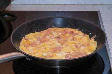 Preparing an egg omelette in a metal pan.