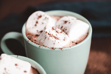 Hot chocolate drink with marshmallow in a cup on wooden board, dark background
