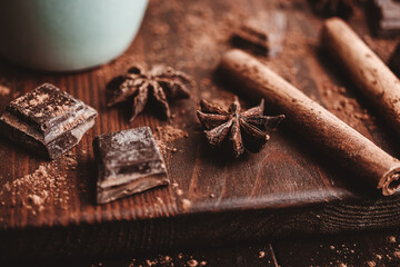 Star anise with cinnamon stick and chocolate cubes on dark rustic wooden background