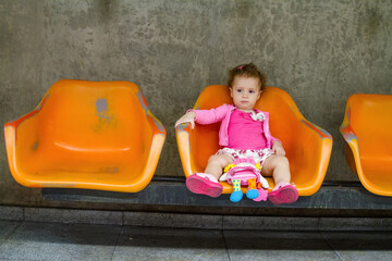 Baby child alone at station, Brazilian baby girl playing with doll centered on station bench