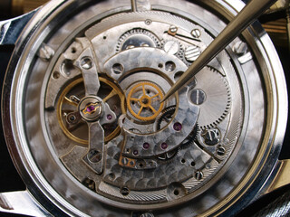 close up pic of wathcmaker repairing vintage mechanical watch mechanism