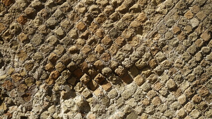 Detail of a wall in a Roman structure built with the opus reticulatum technique in blocks of porphyry, in the archaeological site of Ostia Antica.	