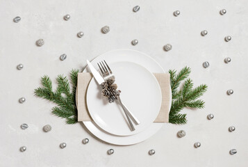 Christmas table setting with silver cutlery and decor on gray background. View from above.