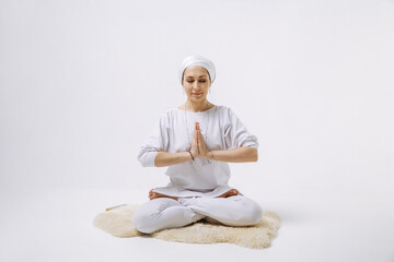 a girl in white clothes does yoga on a white background