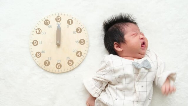 あくびをしている産後1か月0歳の新生児の横に時計を配置した動画