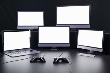 Streaming videogames and gaming concept with blank white glowing modern computer and laptops monitors with place for your text in dark empty room with joysticks on the floor. 3D rendering, mockup