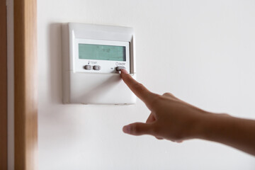 Close-up of a young woman's hand pressing the on/off button of the air conditioner or heater