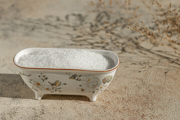 Epsom salt on bowl close up. Magnesium sulfate on beige sunny background. Text space 