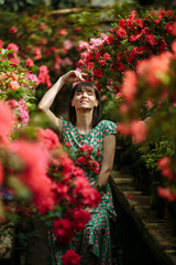 Beautiful brunette in a garden of azaleas in a green dress