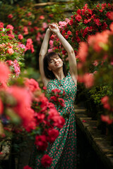 Beautiful brunette in a garden of azaleas in a green dress