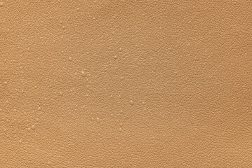Drops of water on light brown leather, background.