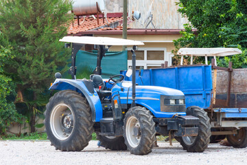 Obraz premium Blue tractor parked next to a rural house.