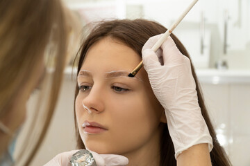 The master lays the client's eyebrows with gel and a brush for fixing the eyebrows, does lamination...