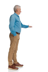 Naklejka premium casual man with grizzled hair holding hand to pocket and showing to side