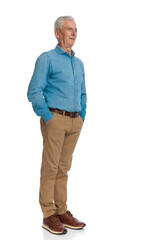 proud man with grey hair holding hands in pockets and looking away