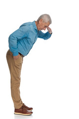 side view of handsome old guy holding hand to forehead and looking down