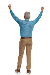 back view of old man with grey hair holding fists above head and celebrating