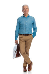 confident man in his 60s with hand in pocket holding bag and smiling