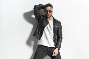 unshaved cool man with sunglasses posing in a cool way with hand behind head
