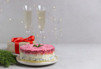 Traditional Russian salad. Layered herring salad under a fur coat on a white plate on a gray background. Russian national cuisine. Selective focus. Copy Space