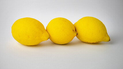 three yellow lemons close up on white background