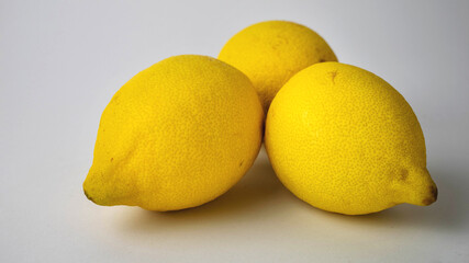 three yellow lemons close up on white background