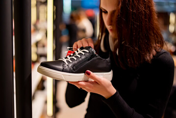 happy young woman choosing sneakers shoes at store
