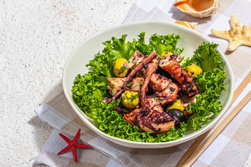 Octopus salad with lettuce, olives and spices in a bowl. Fresh and healthy seafood, marine decor
