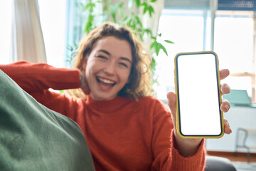 Happy young woman holding mobile phone in hand showing cellphone display, presenting big white...