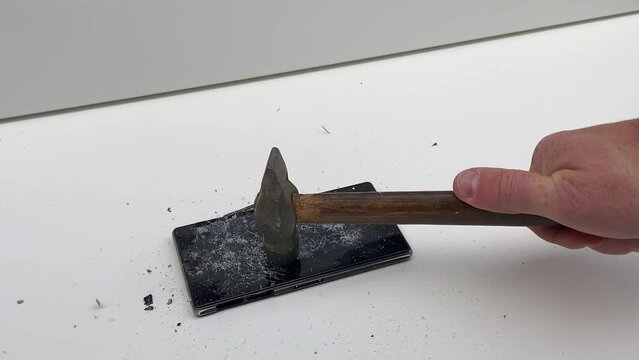 Broken phone. Hammer hitting the display breaks the mobile phone. Mobile smartphone with a broken screen. Drop Test. Hammer Durability. Hammer vs mobile display. Smashing the Phone. Breaking display.