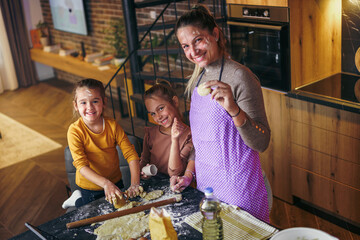 Portrait of a happy family, mother and two daughters, showing off their baking skills