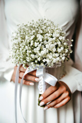 a beautiful white bouquet is held in the hands of a girl in a beautiful white dress