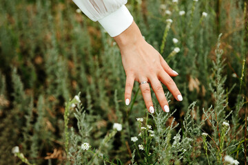 The girl holds her palm over the leaves of juicy greenery