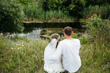 A man hugs his beloved, sitting on the shore of a lake.