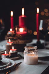Rustic table decor for Christmas or New Year family dinner. Centrepiece with red candle, dry orange, cone, cinnamon, anise. Zero waste eco-friendly home. Cozy atmosphere, dark background. Close up