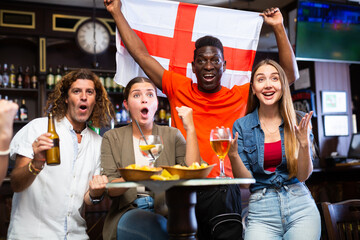 Group of England football team fans spending time in bar, drinking bear and having fun. People with...