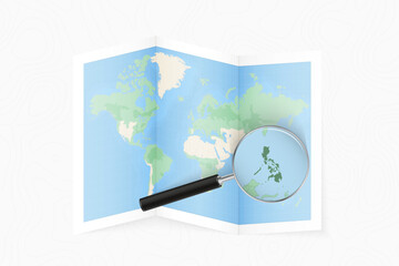 Enlarge Philippines with a magnifying glass on a folded map of the world.