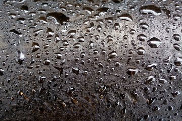 dark drops of oil on a shiny metal surface