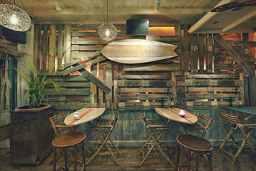 Fototapeta na wymiar Living room of a beach restaurant with similar surfboards as tables and wall decorations