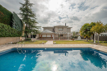 Views of a single-family house with stone floors, a garden with grass and trees on a day full of clouds loaded with water