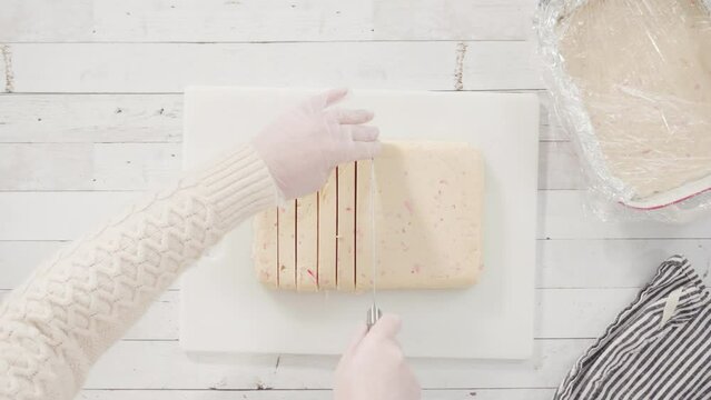 Flat lay. Step by step. Cutting homemade candy cane fudge on a white cutting board.